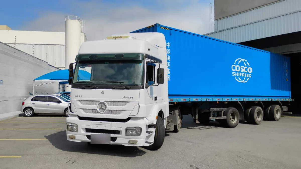 Caminhão transportando contêiner de 40 pés em pátio